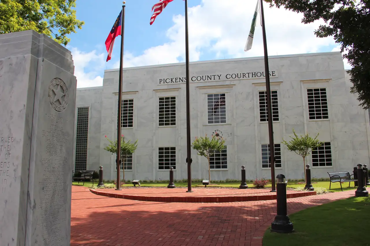 The marble-faced Pickens County Courthouse in Jasper, with three flags flying over a round brick plaza.