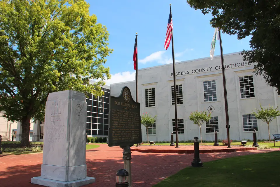 The courthouse square in Jasper with a shade tree, a marble memorial pillar and an Old Federal Road historical marker.