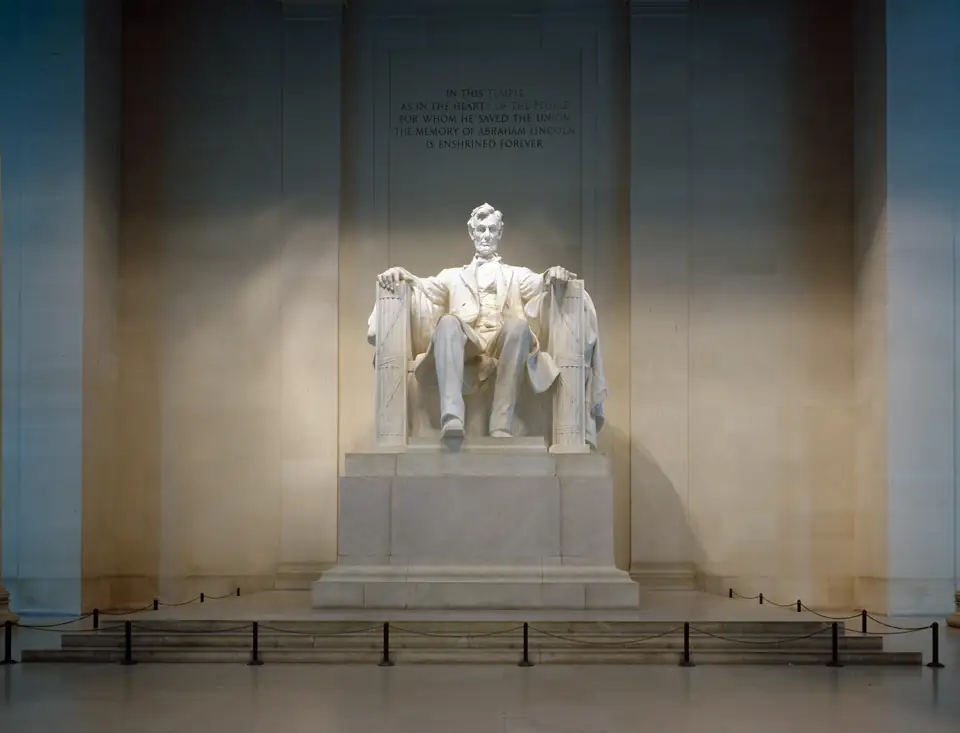The seated marble statue of Abraham Lincoln on a tall pedestal under a carved inscription.