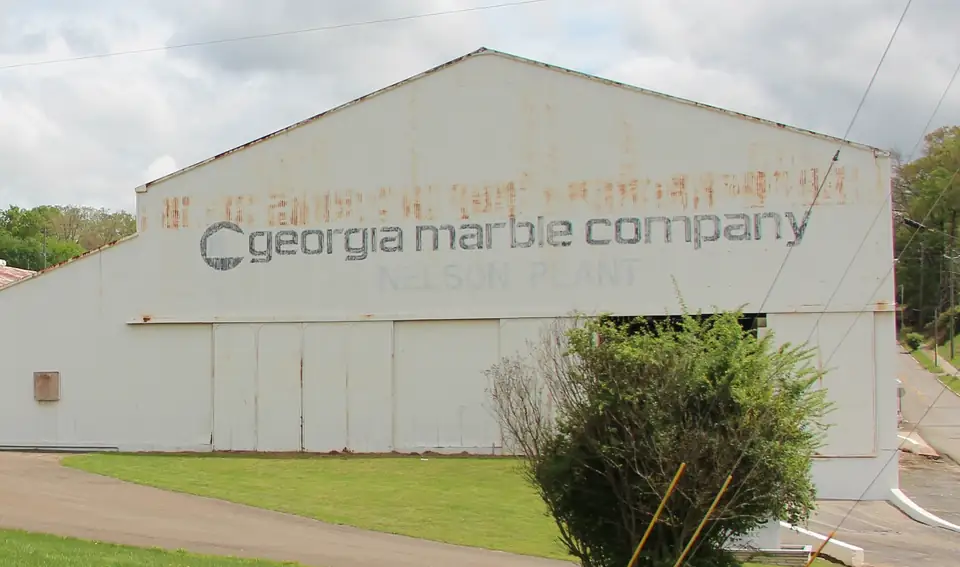 The gable end of a white metal industrial shed painted with the words Georgia Marble Company and Nelson Plant.