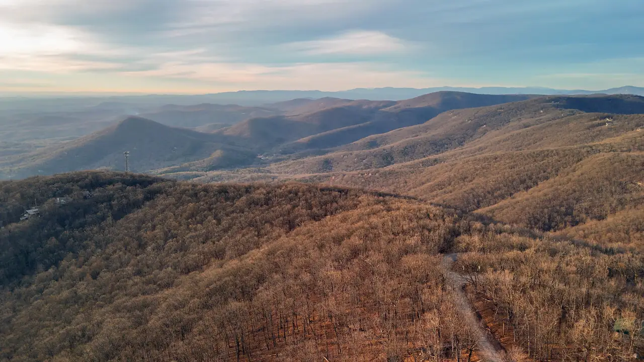A high view over bare winter ridges in tan and russet rolling toward a hazy horizon.