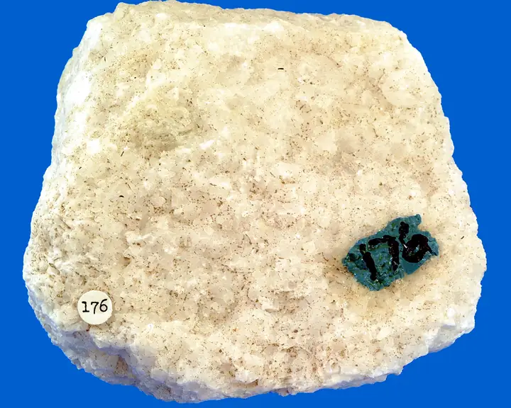 A creamy white, sugary-textured marble specimen with a numbered catalogue sticker.
